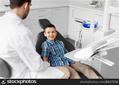 medicine, dentistry and healthcare concept - male dentist talking to kid patient at dental clinic. dentist talking to kid patient at dental clinic. dentist talking to kid patient at dental clinic