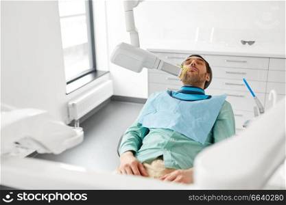medicine, dentistry and healthcare concept - male patient having x-ray scanning procedure at dental clinic. patient having x-ray scanning at dental clinic