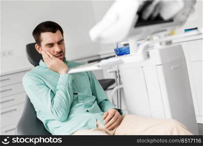 medicine, dentistry and healthcare concept - male patient suffering from toothache at dental clinic office. patient having toothache at dental clinic office. patient having toothache at dental clinic office