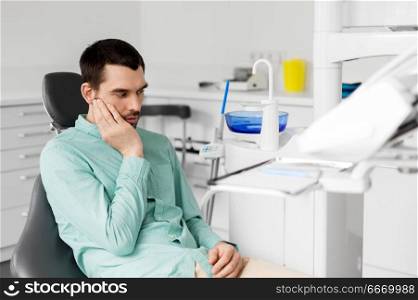 medicine, dentistry and healthcare concept - male patient suffering from toothache at dental clinic office. patient having toothache at dental clinic office. patient having toothache at dental clinic office