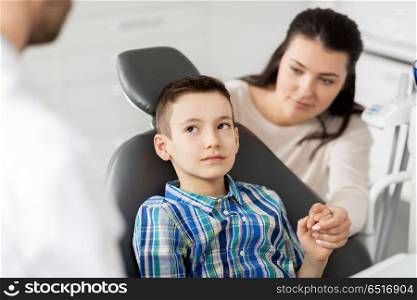 medicine, dentistry and healthcare concept - mother and son visiting dentist at dental clinic. mother and son visiting dentist at dental clinic. mother and son visiting dentist at dental clinic
