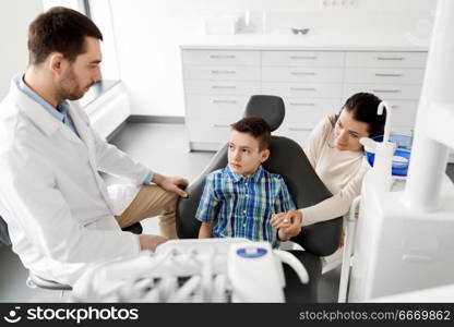 medicine, dentistry and healthcare concept - mother and son visiting dentist at dental clinic. mother and son visiting dentist at dental clinic. mother and son visiting dentist at dental clinic