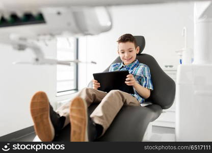 medicine, dentistry and technology concept - happy kid patient with tablet pc computer at dental clinic. happy kid patient with tablet pc at dental clinic. happy kid patient with tablet pc at dental clinic