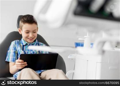 medicine, dentistry and technology concept - happy kid patient with tablet pc computer at dental clinic. happy kid patient with tablet pc at dental clinic. happy kid patient with tablet pc at dental clinic