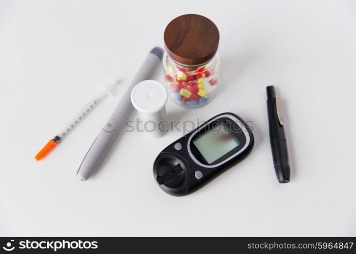 medicine, diabetes and health care concept - close up of glucometer, insulin pen, drug pills and other diabetic tools on table