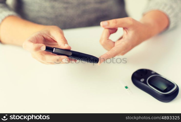 medicine, diabetes, glycemia, health care and people concept - close up of woman checking blood sugar level by glucometer at home