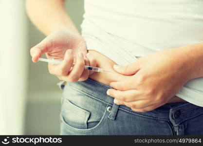 medicine, diabetes, glycemia, health care and people concept - close up of woman with syringe making insulin injection to himself at home. woman with syringe making insulin injection