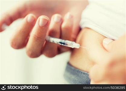 medicine, diabetes, glycemia, health care and people concept - close up of woman with syringe making insulin injection to himself at home. woman with syringe making insulin injection