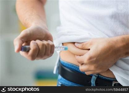 medicine, diabetes, glycemia, health care and people concept - close up of man with syringe making insulin injection to himself at home