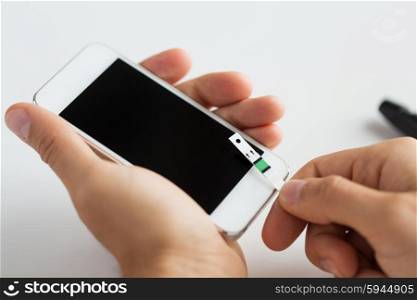 medicine, diabetes, glycemia, health care and people concept - close up of man with smartphone and test stripe checking blood sugar level at home