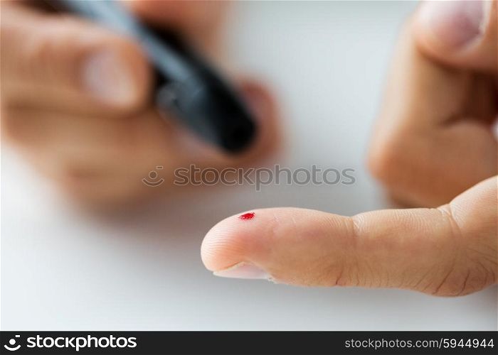 medicine, diabetes, glycemia, health care and people concept - close up of male finger with blood drop and glucometer