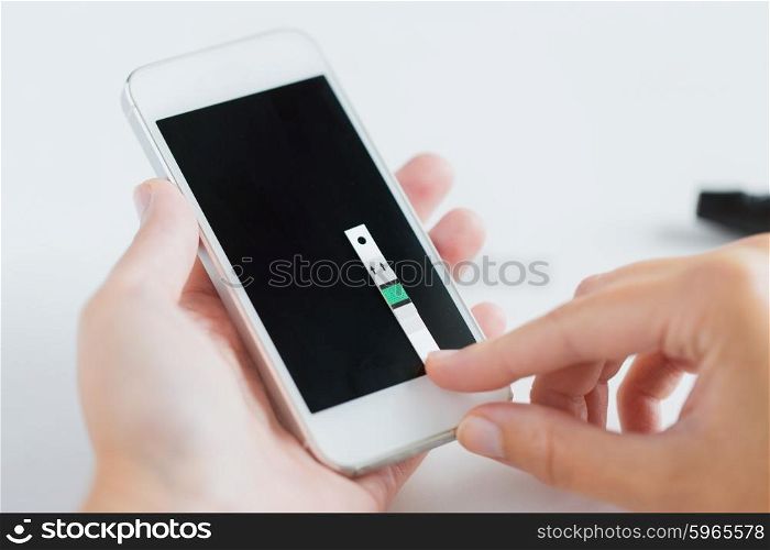 medicine, diabetes, glycemia, health care and people concept - close up of woman hands with smartphone and test stripe checking blood sugar level by glucometer application at home