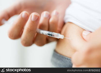 medicine, diabetes, glycemia, health care and people concept - close up of woman with syringe making insulin injection to himself at home