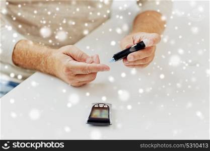 medicine, diabetes, healthcare and old people concept - senior man with glucometer checking blood sugar level at home over snow. senior man with glucometer checking blood sugar