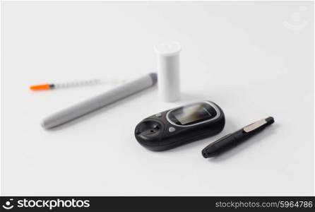 medicine, diabetes, medical tool and health care concept - close up of glucometer, insulin pen and syringe on table