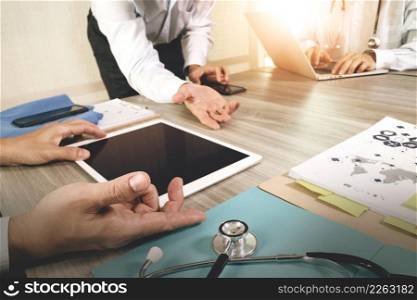 Medicine doctor hand working with modern computer and digital pro tablet with blank screen with his team on wooden desk as medical concept