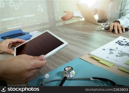 Medicine doctor hand working with modern computer and digital pro tablet with blank screen with his team on wooden desk as medical concept