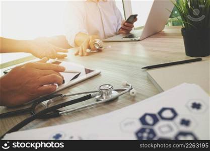 Medicine doctor hand working with modern computer and digital tablet with his team on wooden desk as medical concept