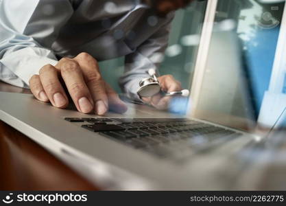 Medicine doctor hand working with modern computer and medical diagram layers on wooden desk as medical concept