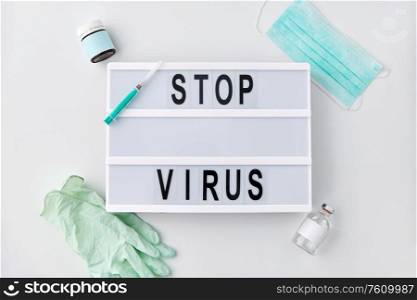 medicine, epidemic and healthcare concept - lightbox with stop virus caution words, protective mask, gloves and syringe with drug on white background. lightbox with stop virus caution words