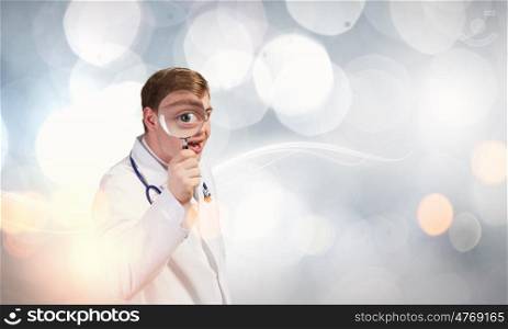 Medicine exploration. Funny young doctor with magnifier expecting something