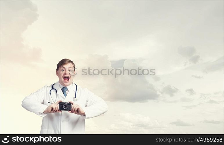 Medicine exploration. Funny young doctor with photo camera screaming emotionally