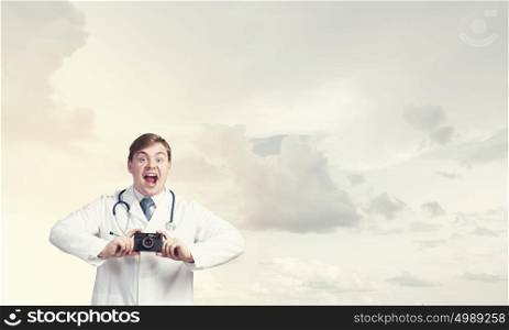 Medicine exploration. Funny young doctor with photo camera screaming emotionally
