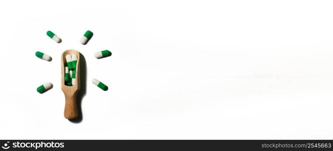 medicine green pills on white background on wooden spoon in the form of a light bulb . Copy space for text. banner. medicine green pills on white background on a wooden spoon in the form of a light bulb . Copy space for text. banner