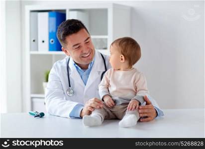 medicine, healtcare, pediatry and people concept - happy doctor or pediatrician holding baby on medical exam at clinic. happy doctor or pediatrician with baby at clinic