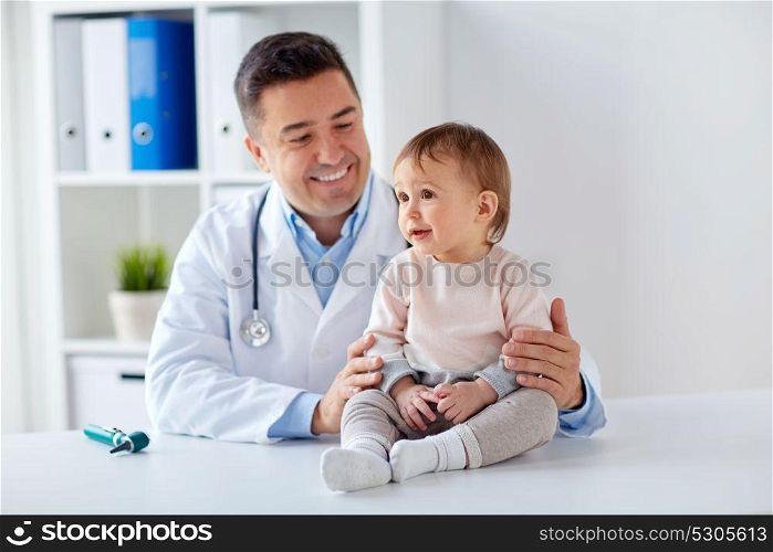 medicine, healtcare, pediatry and people concept - happy doctor or pediatrician holding baby on medical exam at clinic. happy doctor or pediatrician with baby at clinic