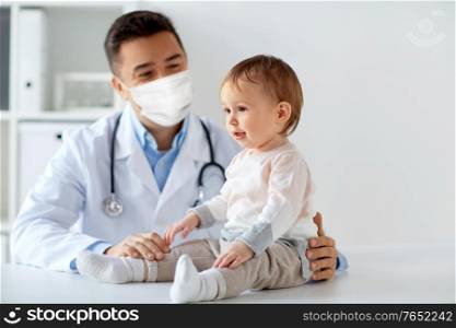 medicine, healtcare, pediatry and people concept - happy doctor or pediatrician wearing face protective mask for protection from virus disease with baby on medical exam at clinic. doctor or pediatrician in mask with baby at clinic