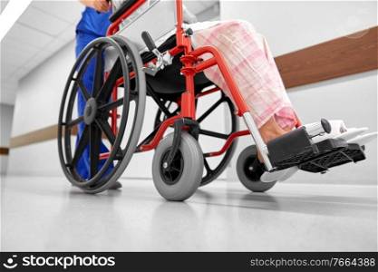 medicine, health and care concept - nurse taking senior woman patient in wheelchair at hospital corridor or nursing home. nurse with senior patient in wheelchair at clinic