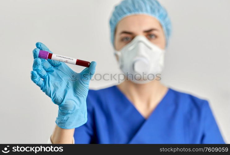 medicine, health and pandemic concept - close up of young female doctor or nurse holding beaker with coronavirus blood test. doctor holding beaker with coronavirus blood test