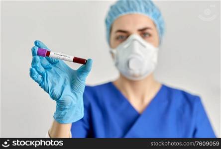 medicine, health and pandemic concept - close up of young female doctor or nurse holding beaker with coronavirus blood test. doctor holding beaker with coronavirus blood test