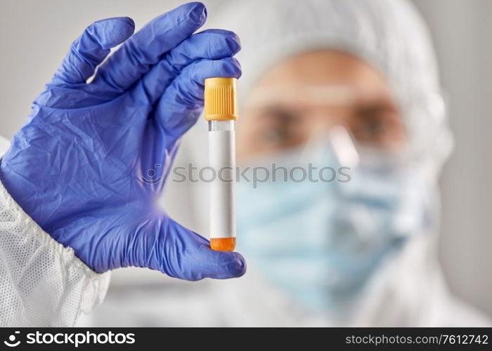 medicine, health and pandemic concept - close up of young female doctor or scientist in face protective medical mask, goggles and gloves holding beaker with virus test. scientist in protective mask with test tube