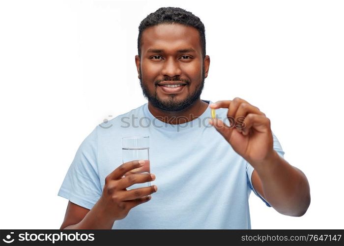 medicine, health and people concept - happy smiling african american man with pill and glass of water over white background. african american man with pill and glass of water