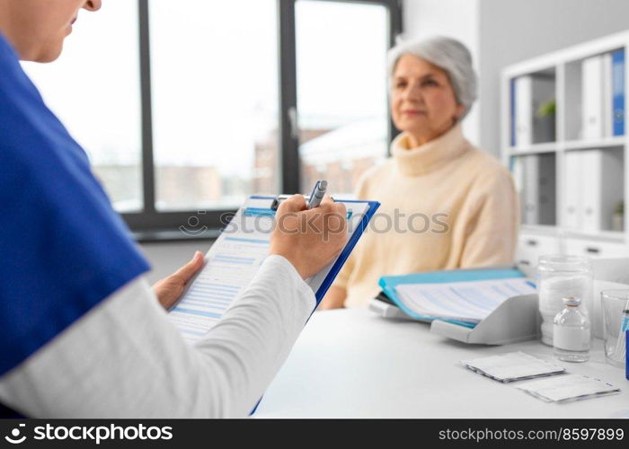 medicine, health and vaccination concept - close up of doctor with clipboard and senior woman at hospital. doctor with clipboard and senior woman at hospital