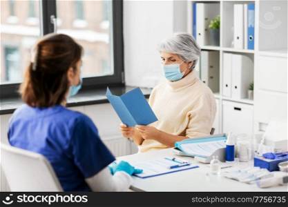 medicine, health and vaccination concept - doctor or nurse and senior woman reading medical brochure at hospital. doctor and senior woman reading medical brochure