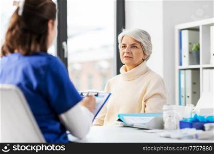 medicine, health and vaccination concept - doctor with clipboard and senior woman at hospital. doctor with clipboard and senior woman at hospital