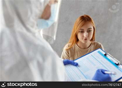 medicine, health and virus concept - patient and doctor or healthcare worker in protective wear writing medical report on clipboard and making coronavirus test. patient being tested for coronavirus disease