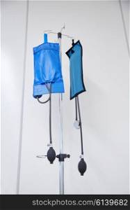 medicine, health care and medical equipment concept - two sphygmomanometers or pressure infusion cuffs hanging on holder at hospital