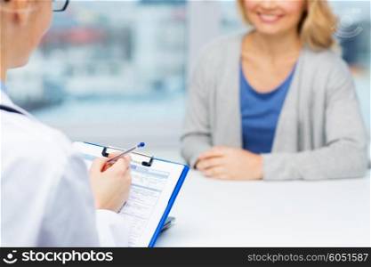 medicine, health care and people concept - close up of doctor with clipboard and young woman patient meeting at hospital