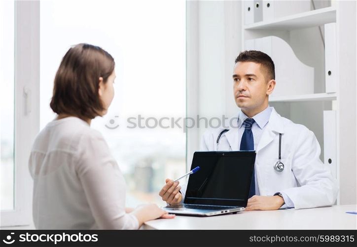 medicine, health care and people concept - doctor showing to woman blank laptop computer screen and meeting at hospital
