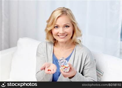 medicine, health care and people concept - happy middle aged woman with medicine at home