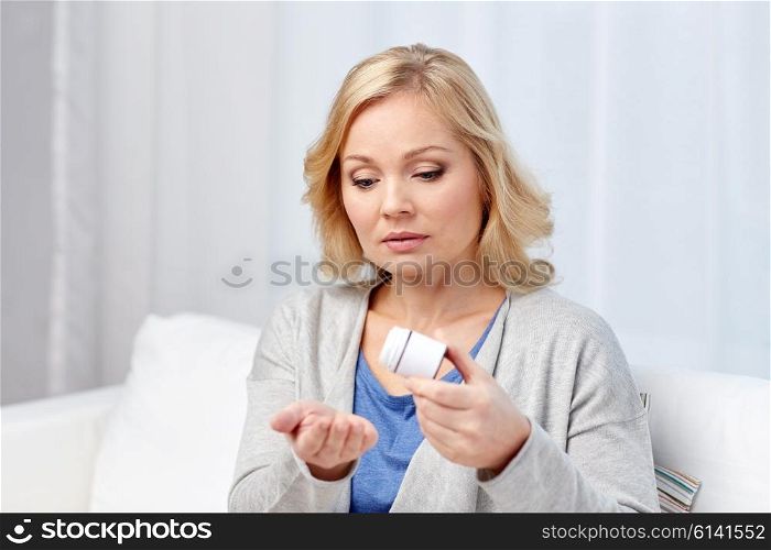 medicine, health care and people concept - middle aged woman with medicine at home