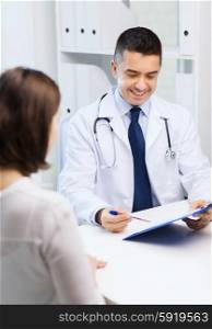 medicine, health care and people concept - smiling doctor with clipboard and young woman meeting at hospital