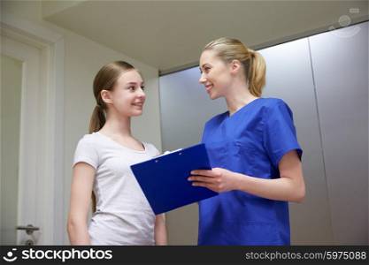 medicine, health care and people concept - smiling female doctor or nurse with clipboard and young girl meeting at hospital