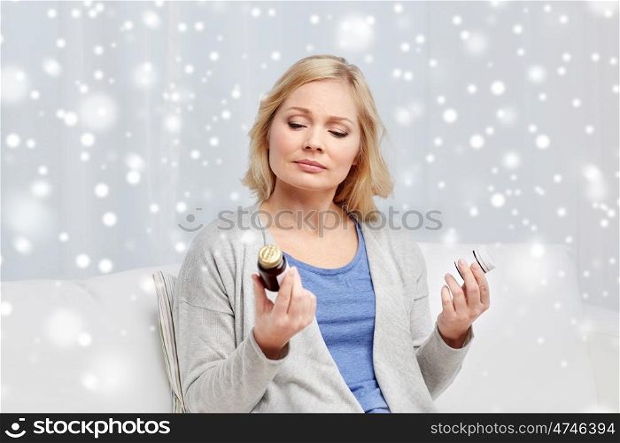 medicine, health care and people concept - woman looking at jars with medication at home over snow