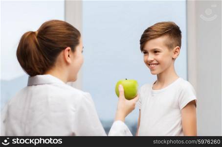 medicine, health care, dentistry, diet and people concept - doctor or dentist with green apple and happy boy in clinic