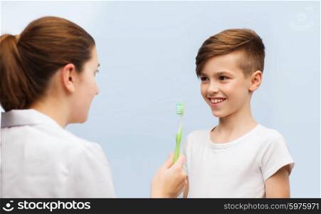 medicine, health care, dentistry, hygiene and people concept - doctor or dentist with toothbrush and happy boy in clinic